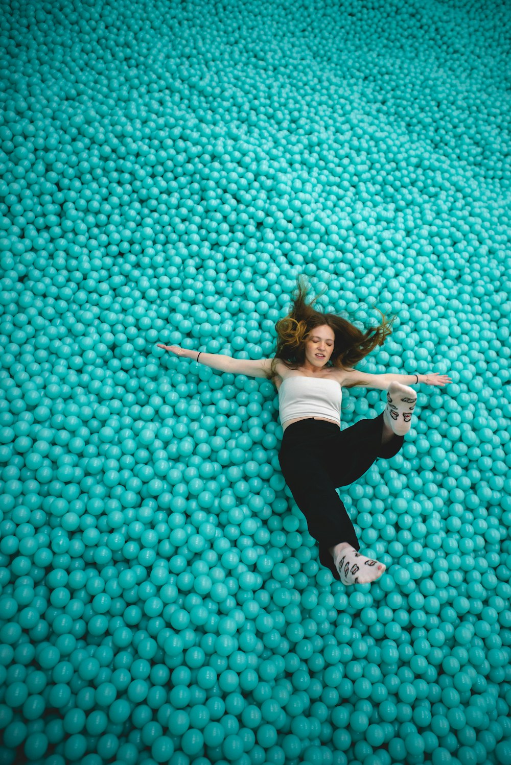 woman in white shirt and black pants lying on blue and white floor