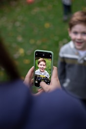 man in white shirt holding black iphone 5