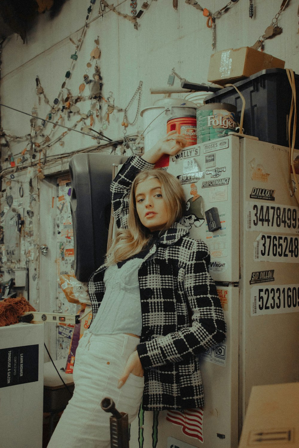 woman in white and black plaid dress shirt and white pants holding black and gray corded