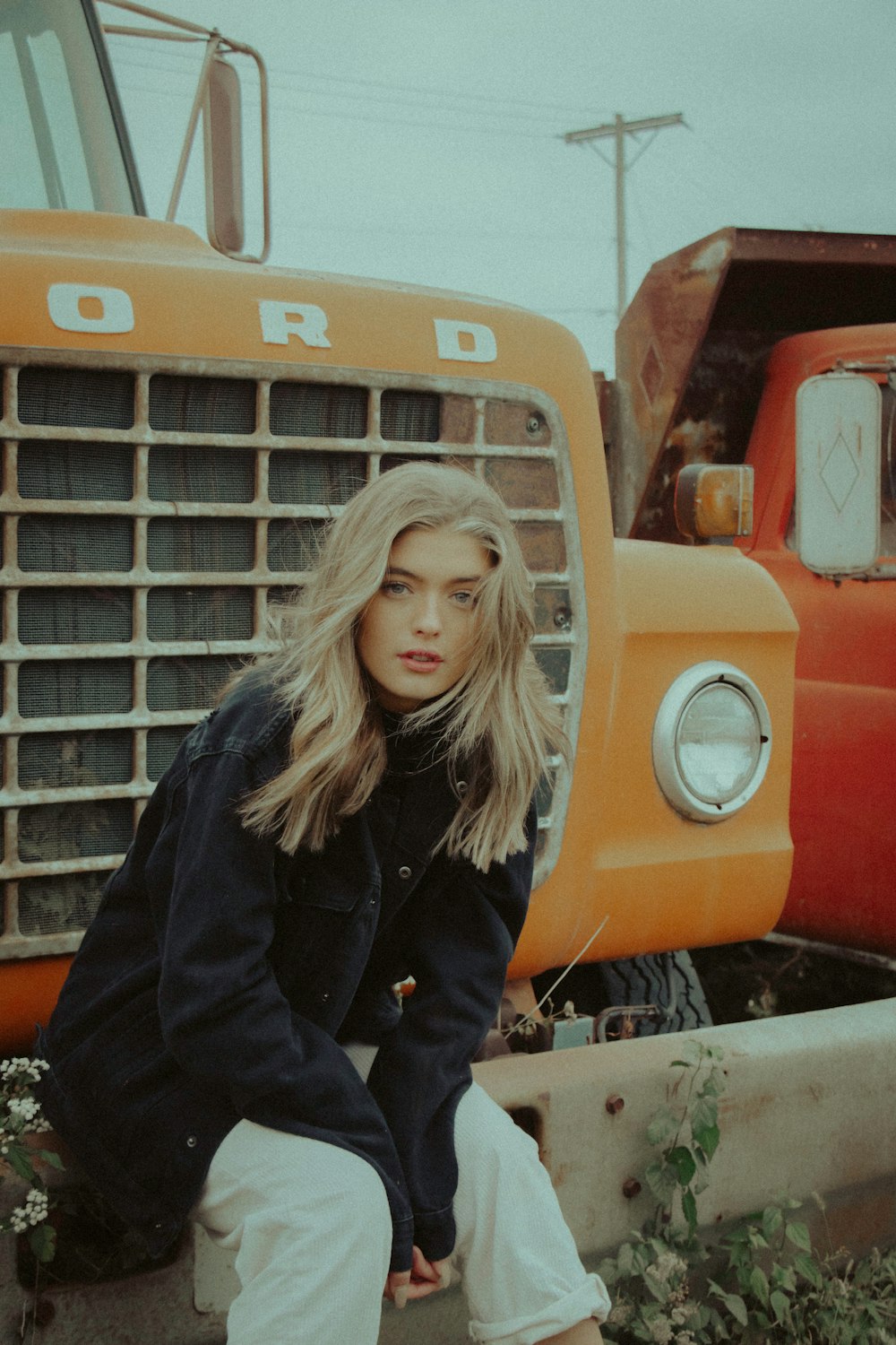 woman in black jacket standing beside orange car