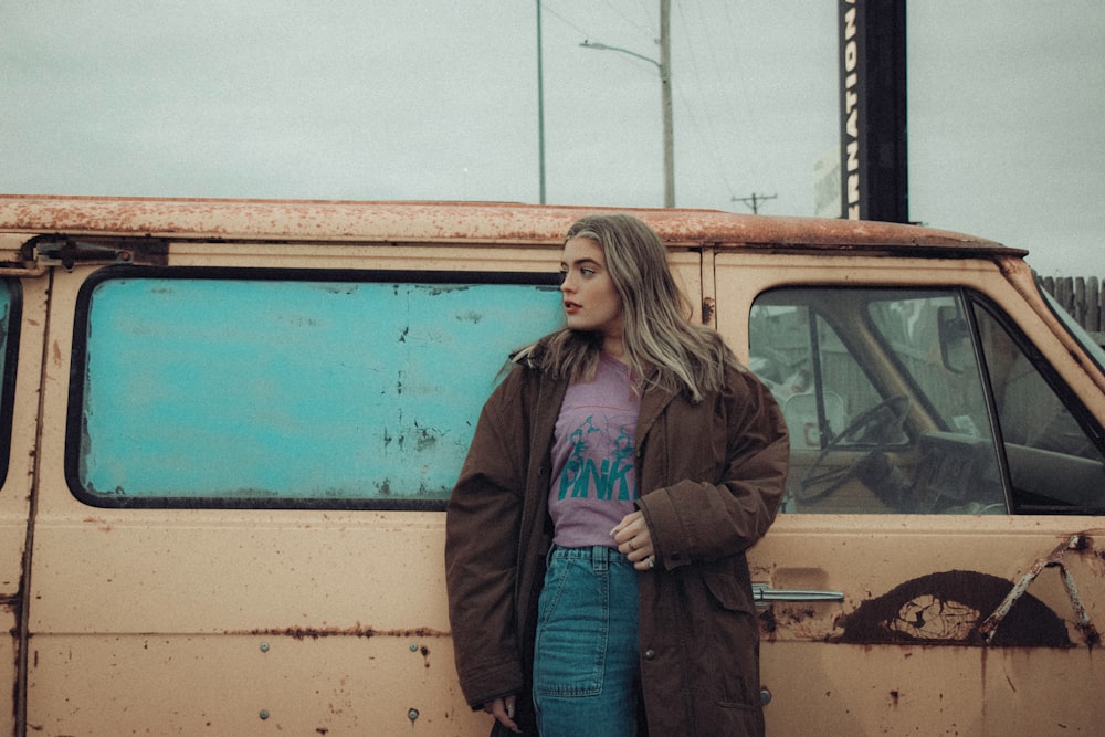 woman in brown coat standing beside brown car