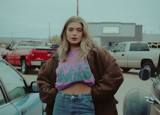 woman in brown jacket standing beside black car