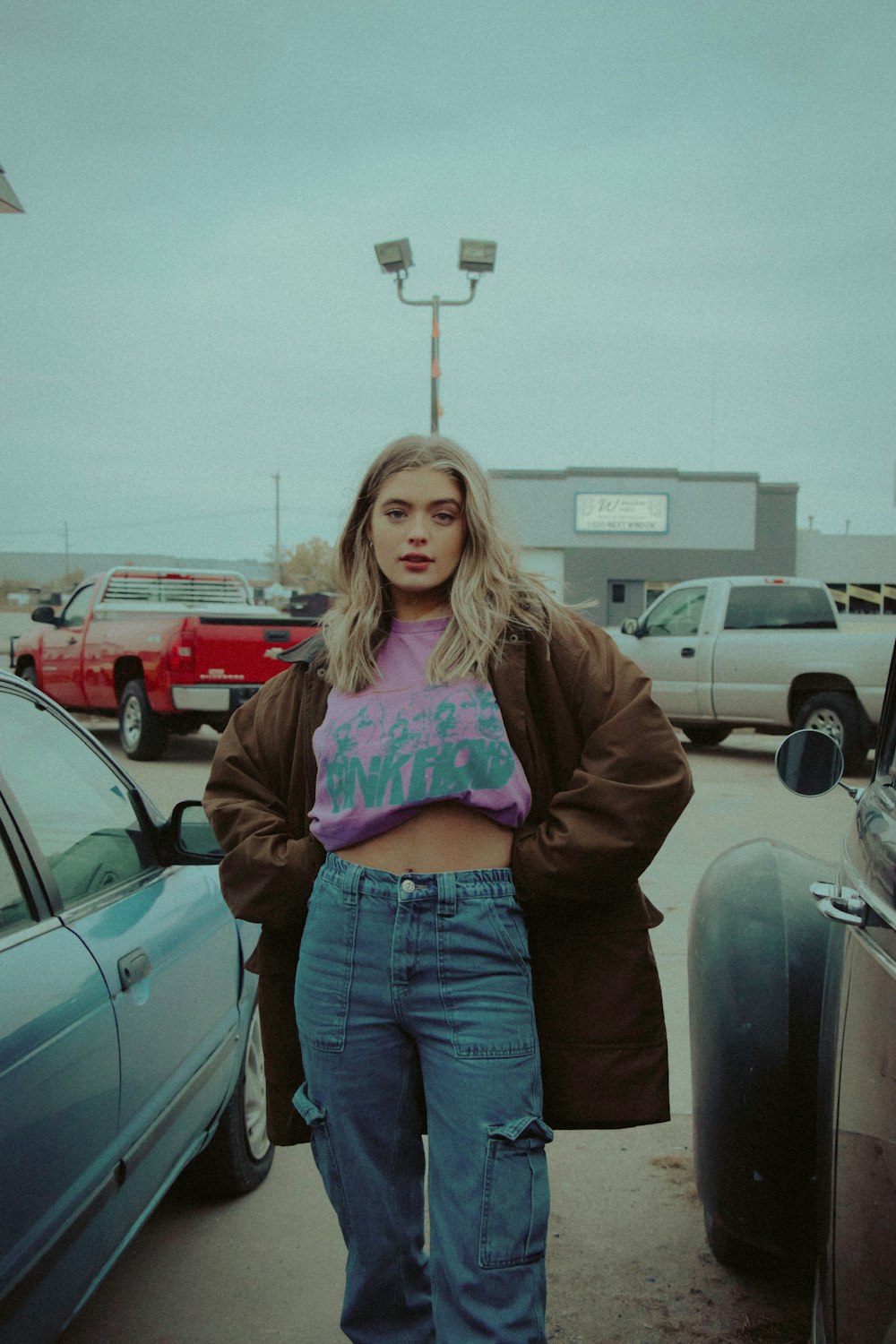 woman in brown jacket standing beside black car