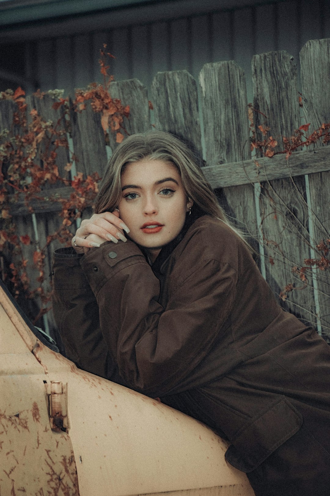 woman in brown coat sitting on brown wooden bench