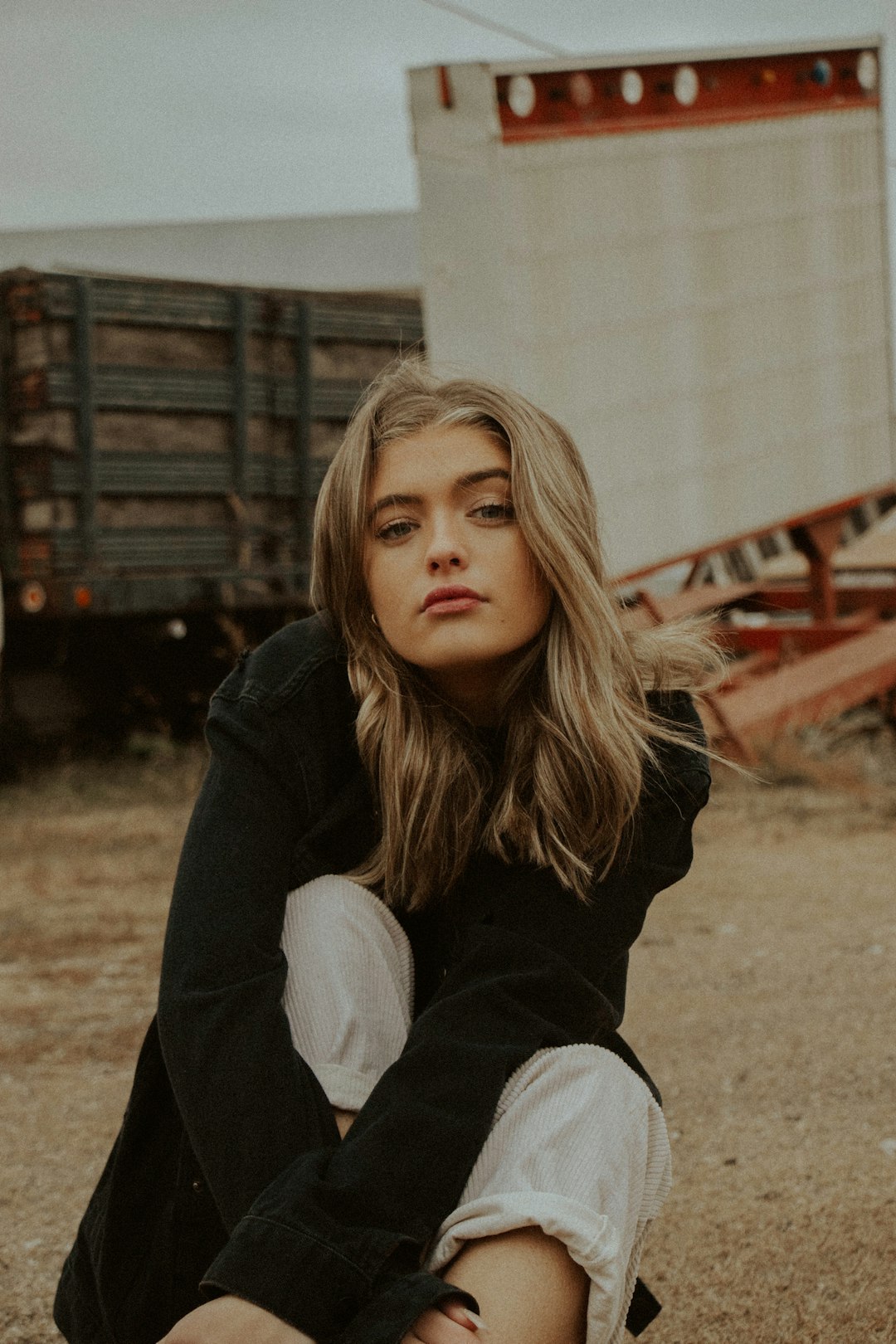 woman in black hoodie sitting on ground during daytime