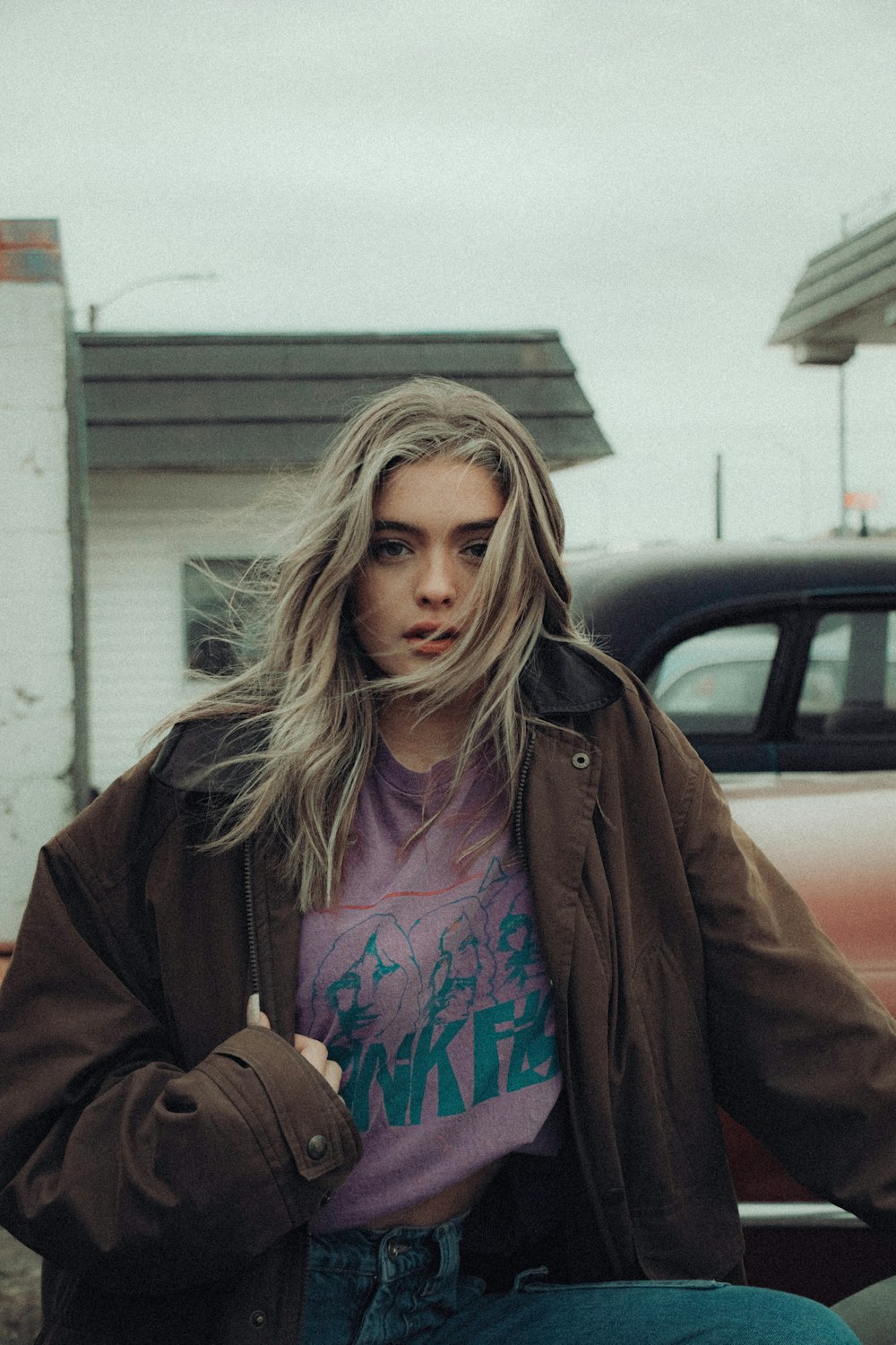 woman in brown jacket standing near black car