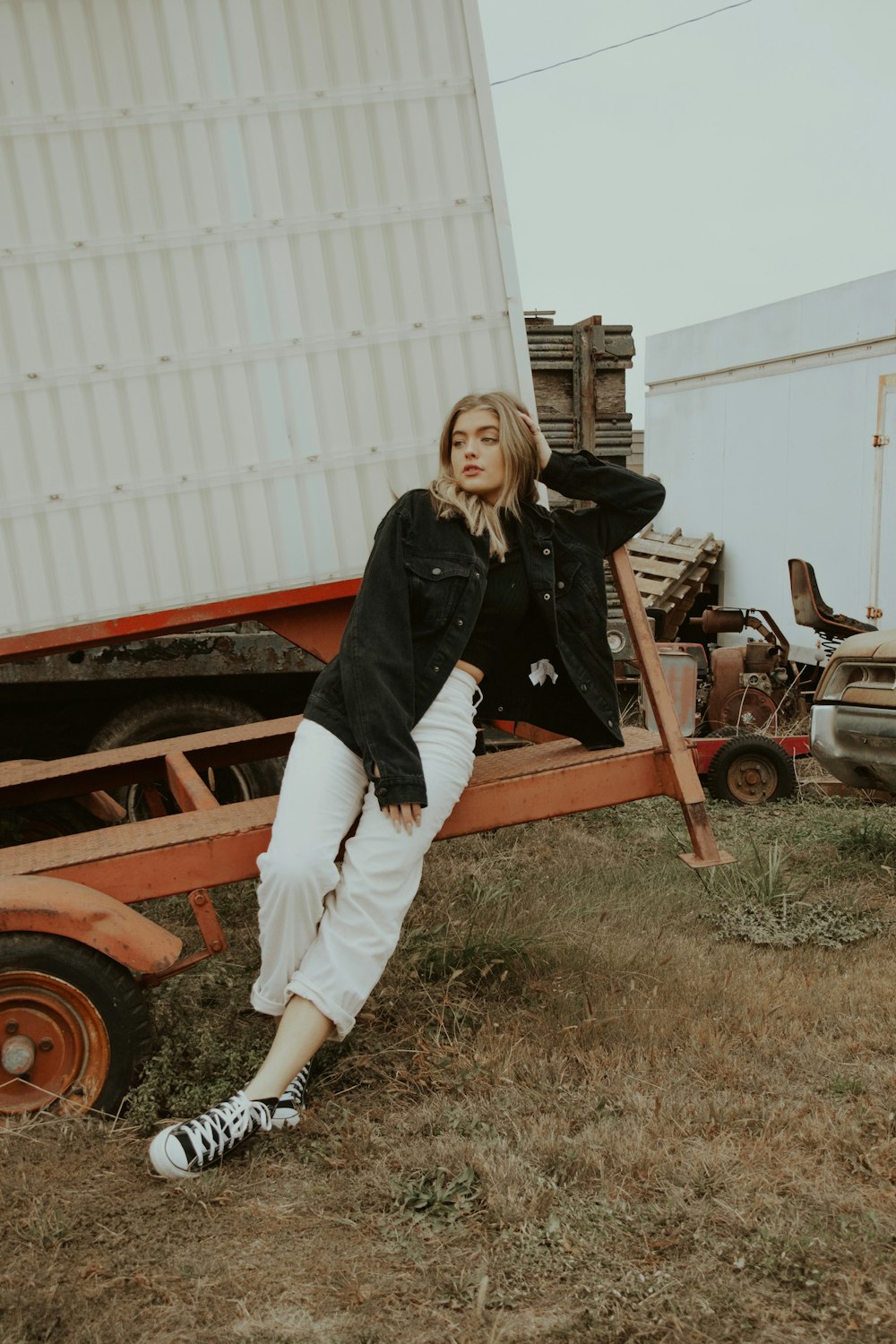 woman in black jacket and white pants sitting on brown wooden bench