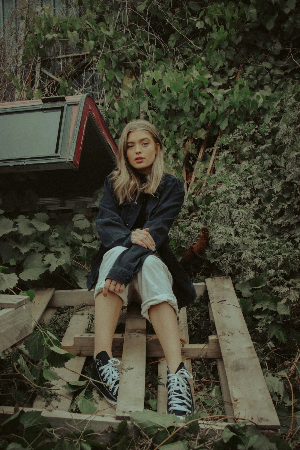 woman in blue denim jacket sitting on brown wooden bench