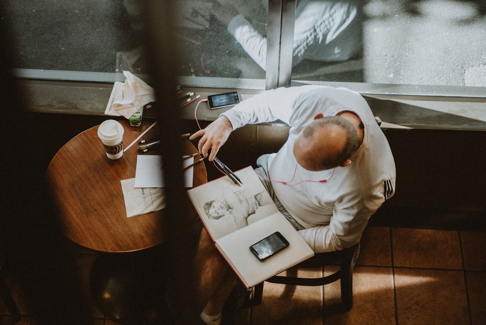 man in white dress shirt writing on white paper