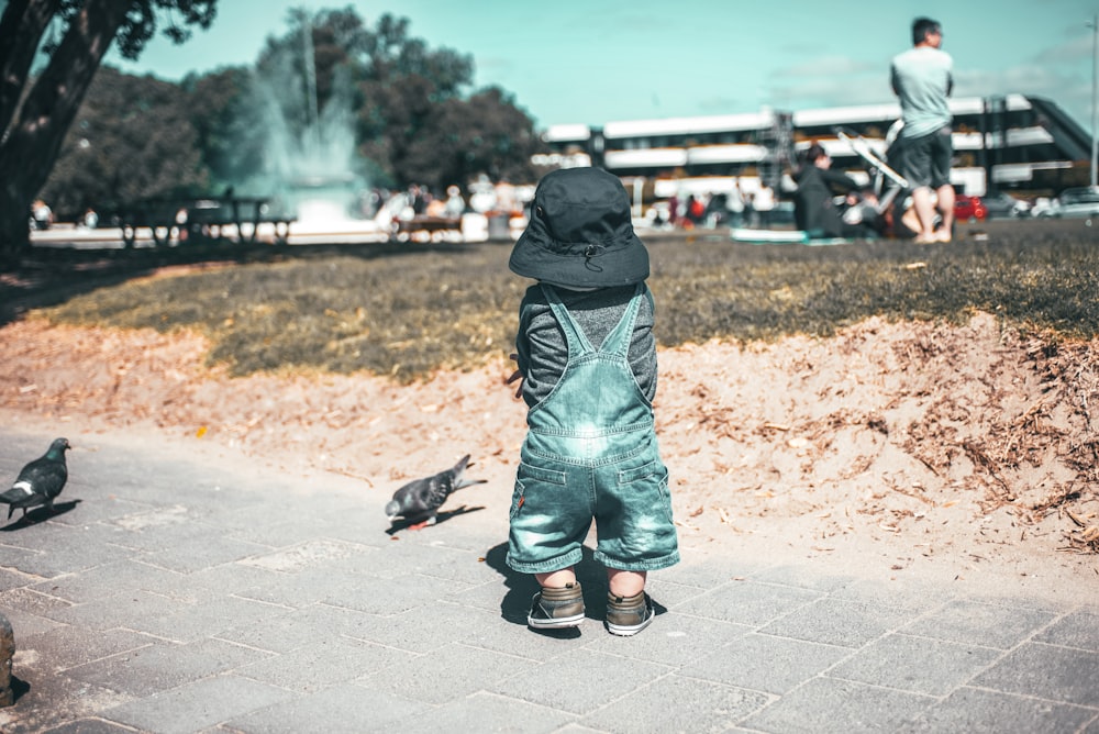 person in blue denim jeans and black shoes standing on brown soil during daytime