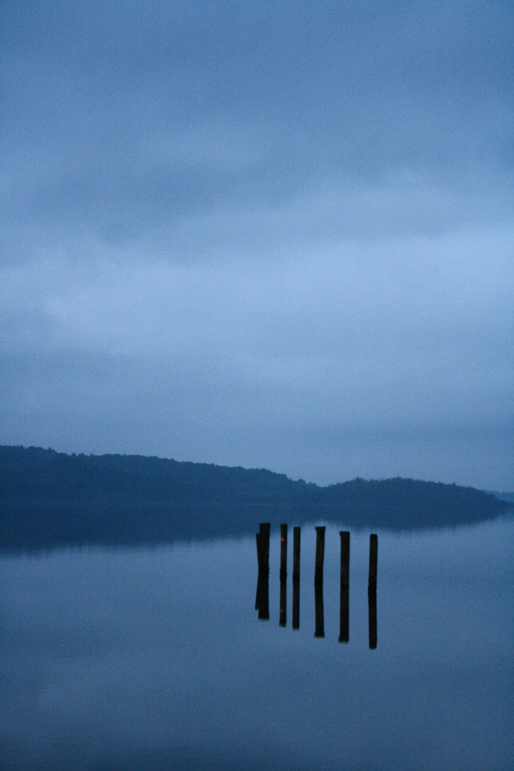 brown wooden fence on body of water under white clouds