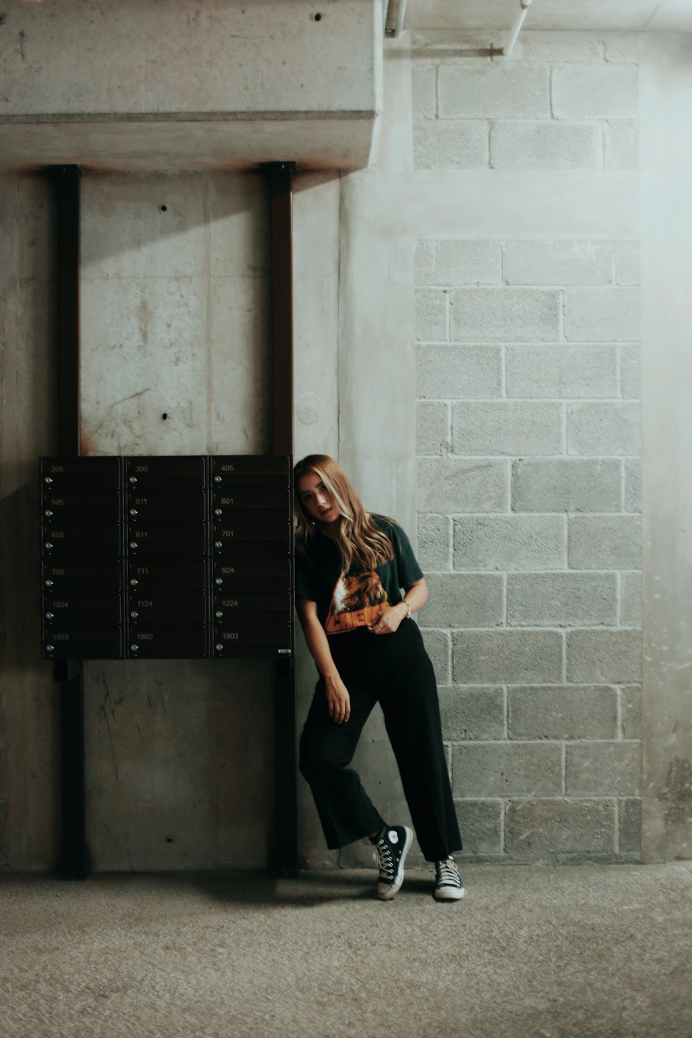 woman in black pants and black leather boots sitting on black wooden cabinet