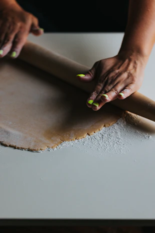 person holding brown wooden rolling pin