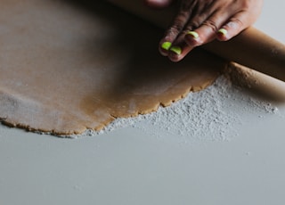 person holding brown wooden rolling pin