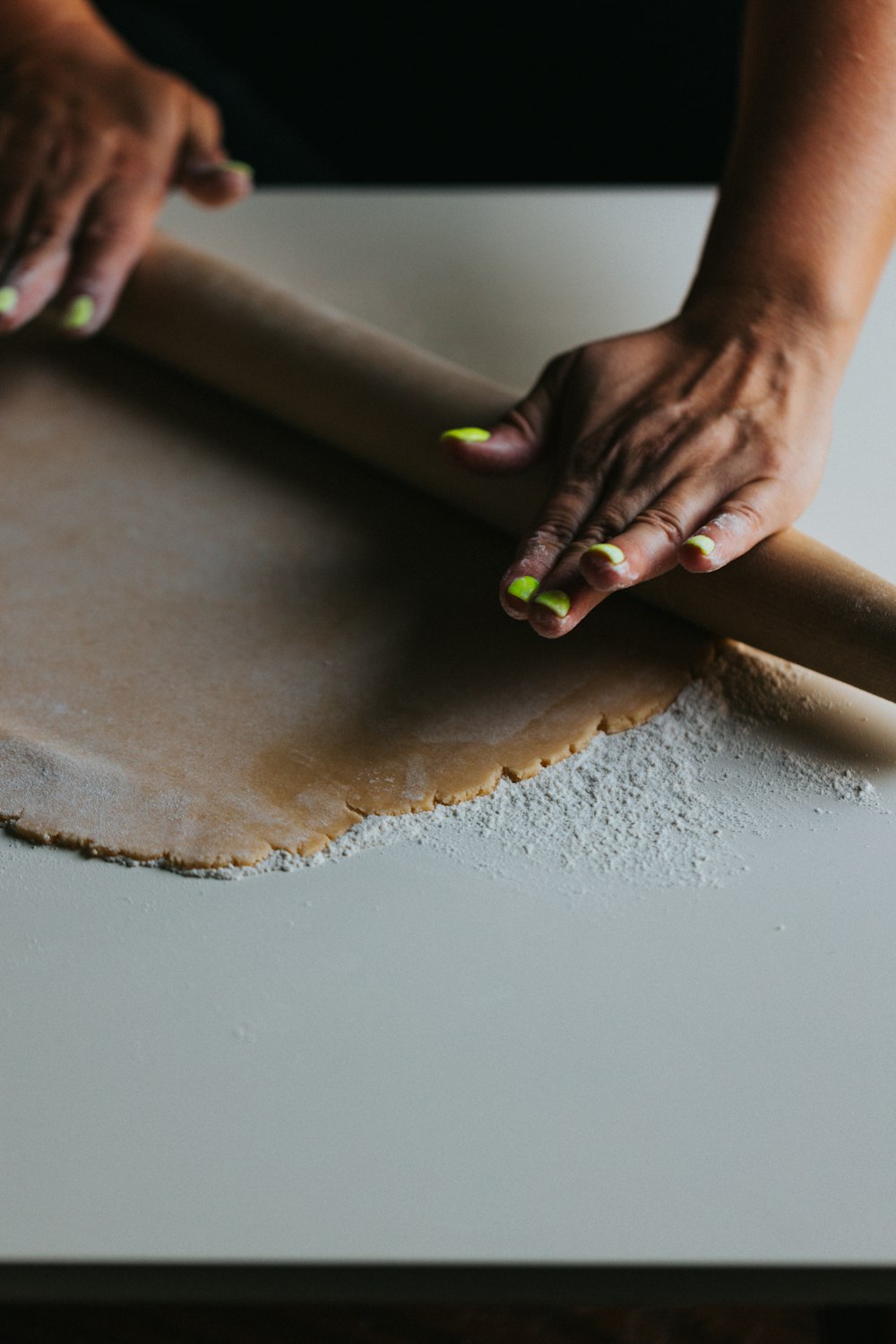 person holding brown wooden rolling pin