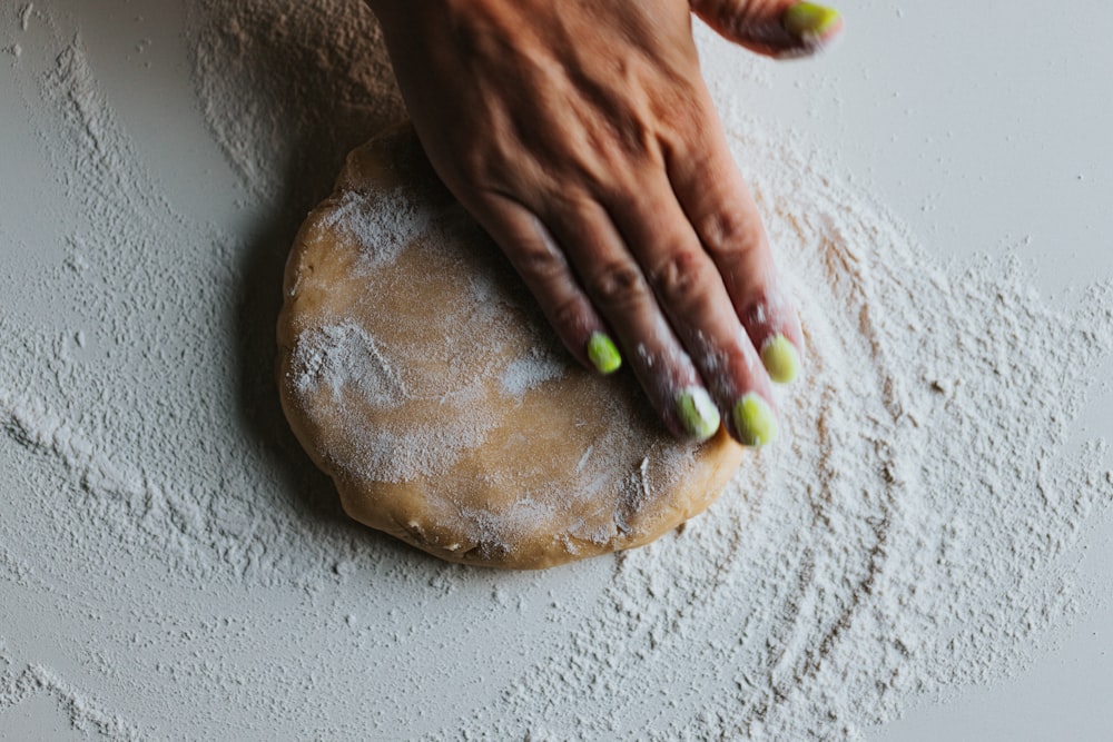 person holding brown bread with green and yellow powder