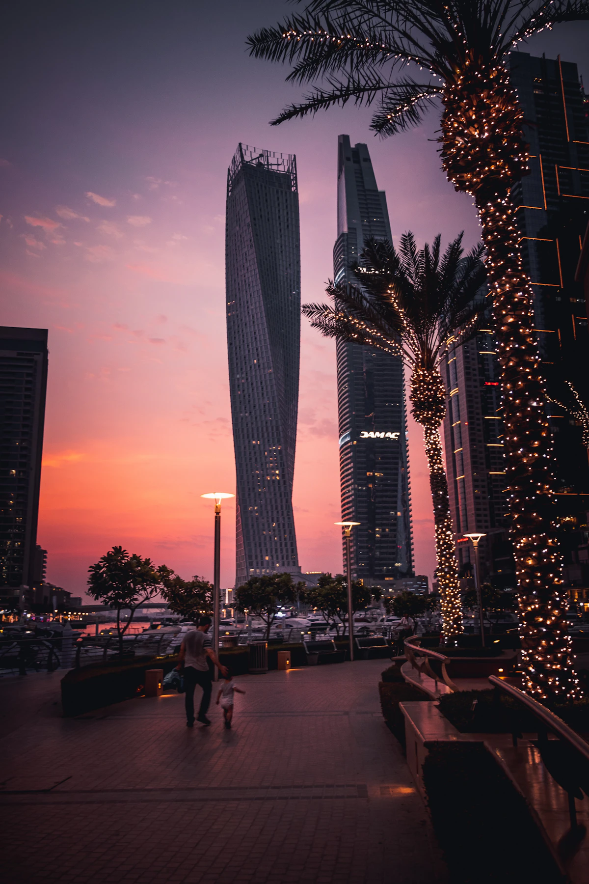 People walking near high-rise buildings at Dubai Marina in the evening