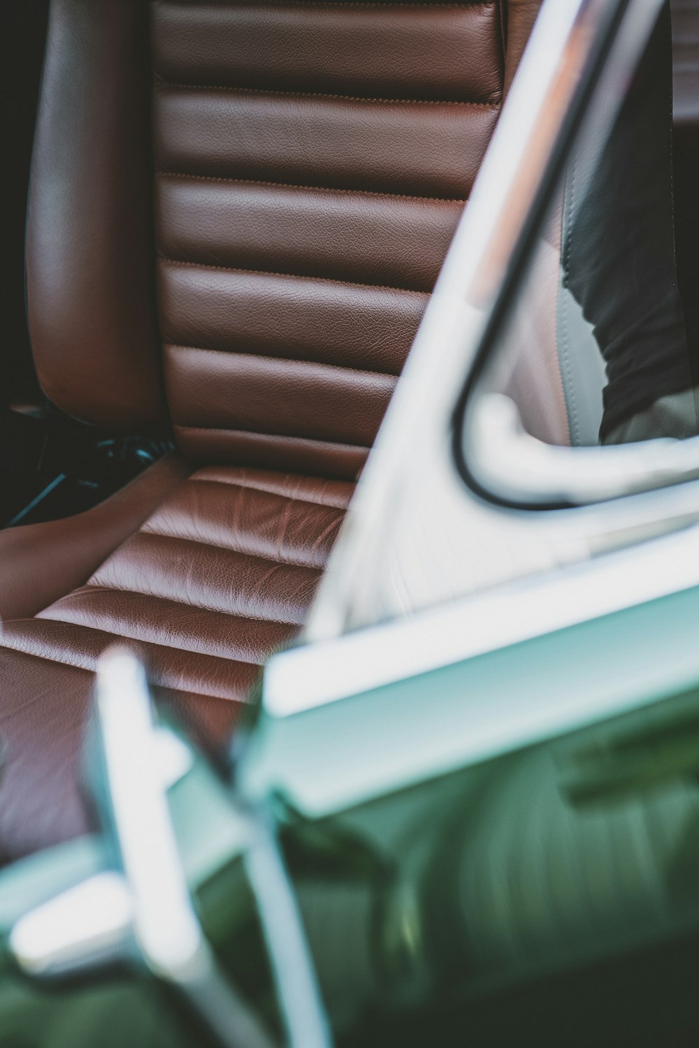 person in black pants sitting on brown leather car seat