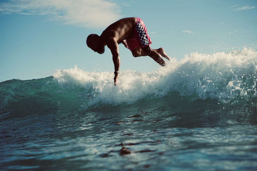 man in red and white shorts surfing on water during daytime