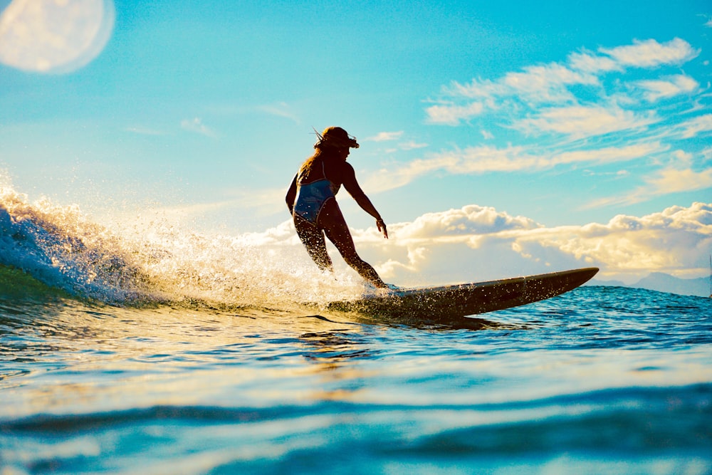 woman in blue and white bikini surfing on sea waves during daytime