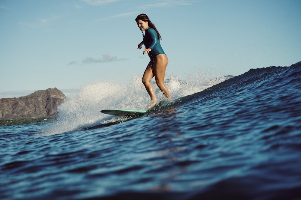 woman in blue bikini surfing on sea during daytime