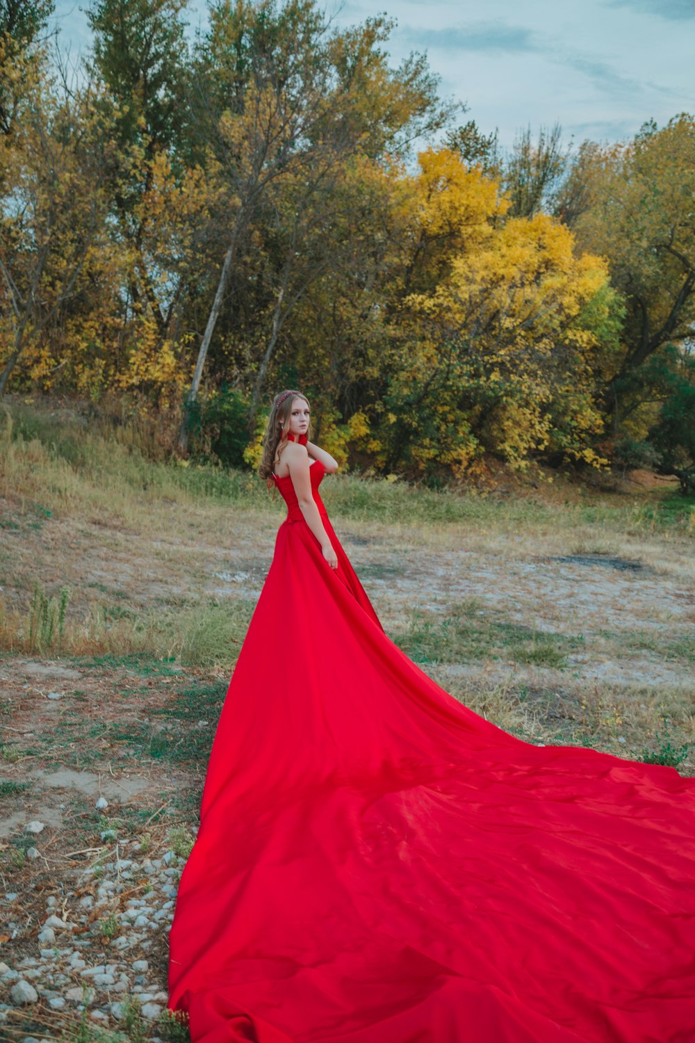 woman in red dress standing on green grass field during daytime