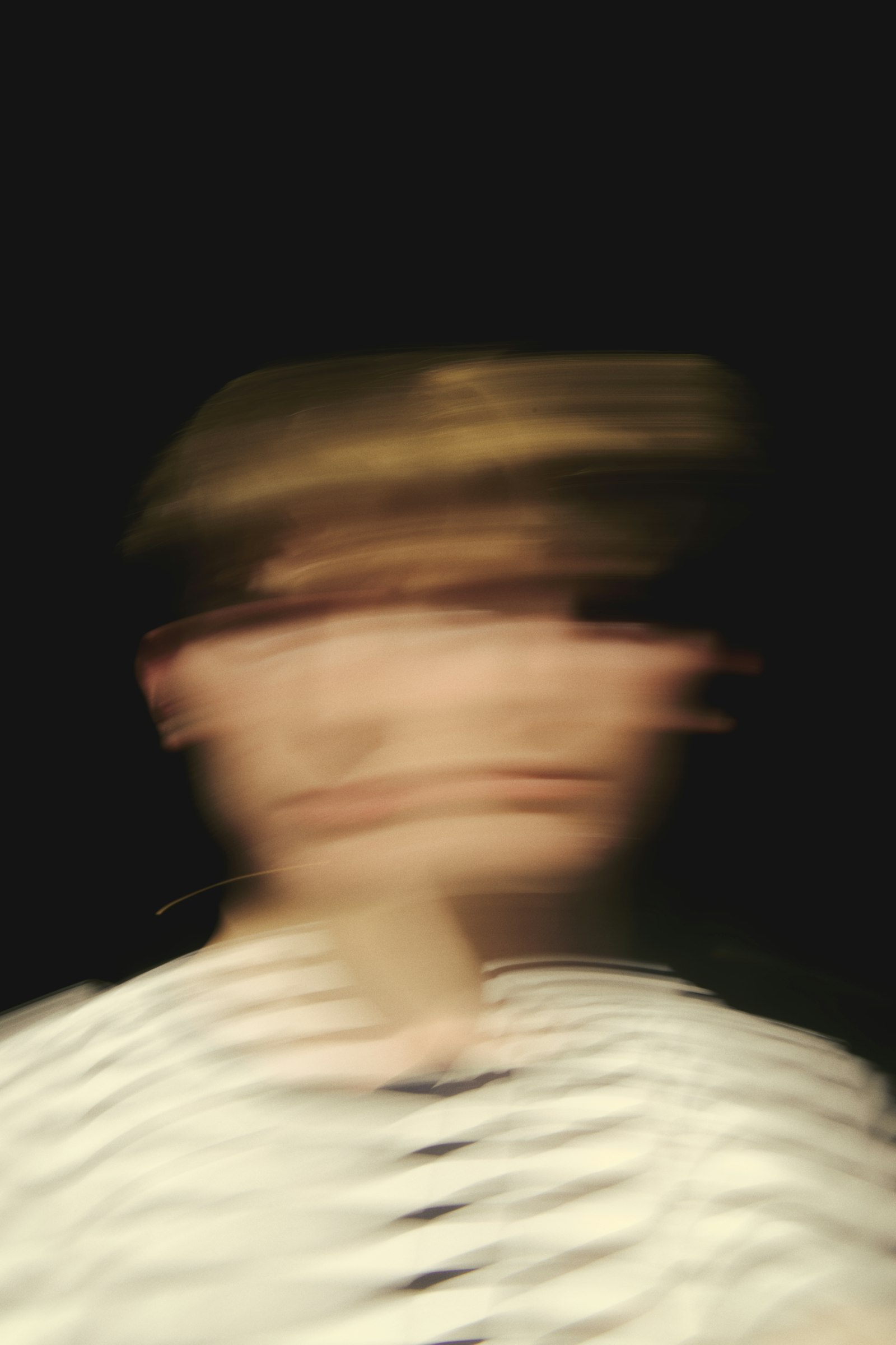 A motion-blurred portrait of a person, the face dissolved by movement