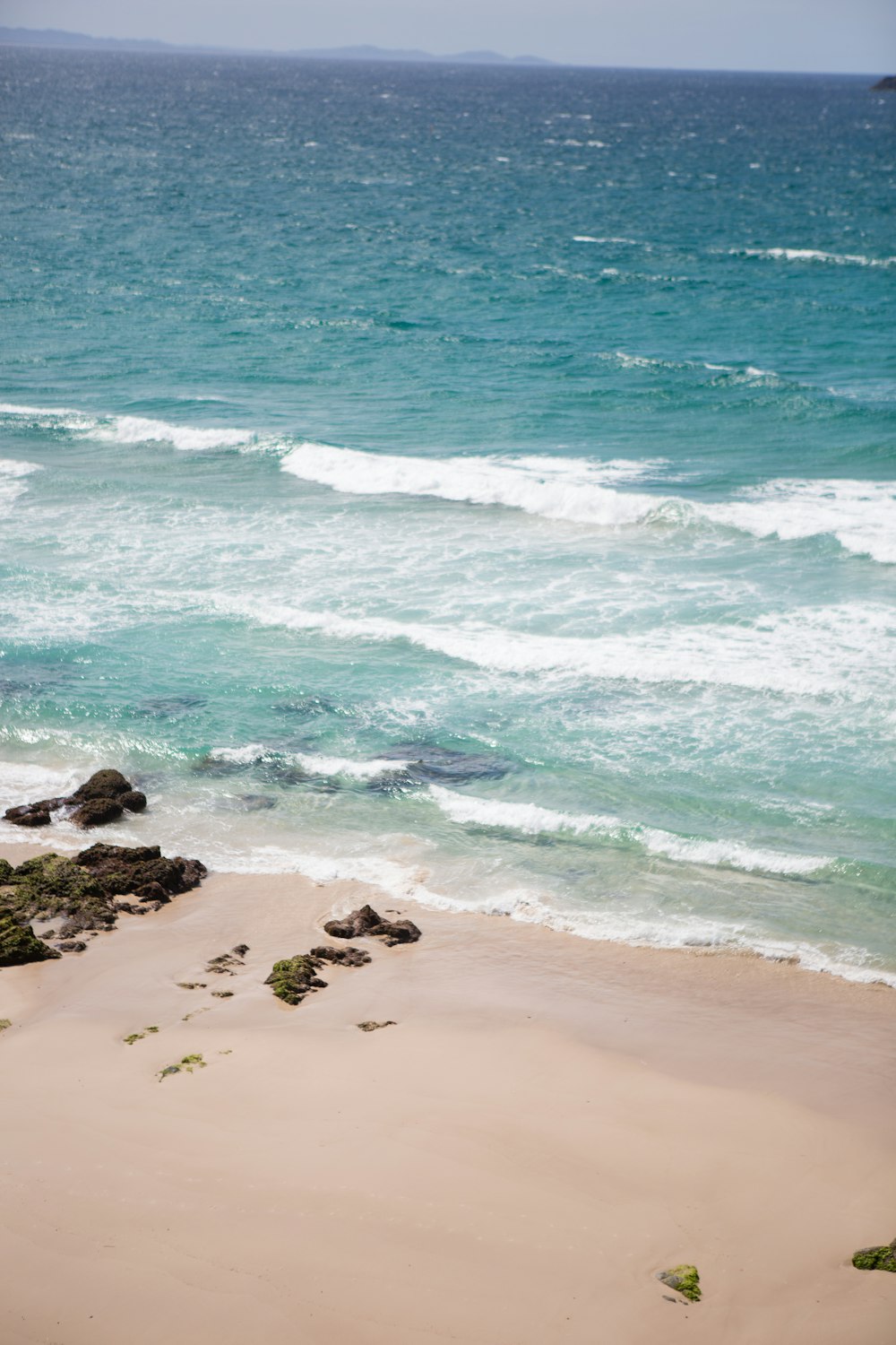 brown sand beach with rocks