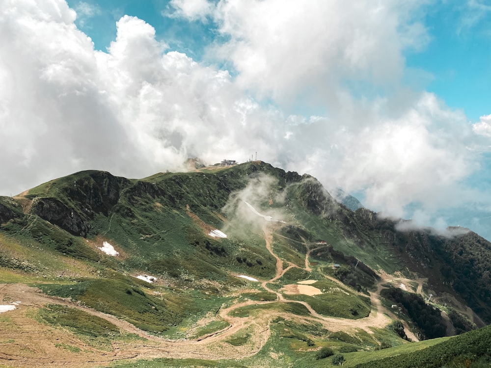 昼間の白い雲と青い空の下に緑と茶色の山