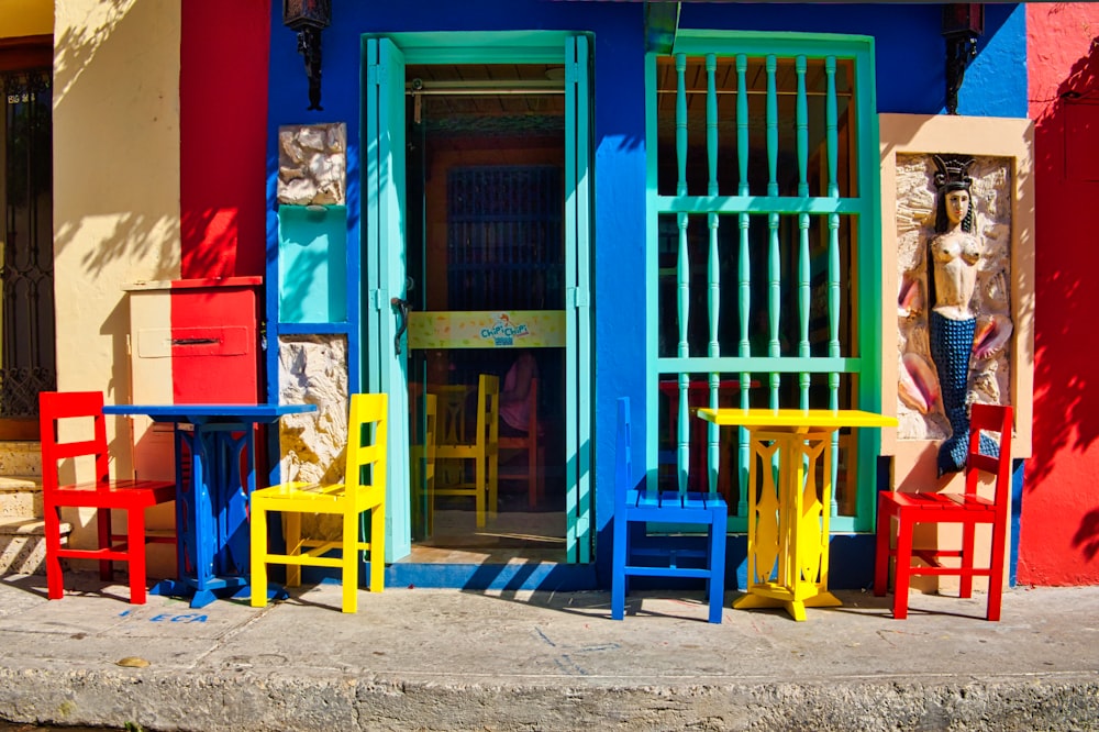 puerta de madera azul con sillas de madera rojas y azules