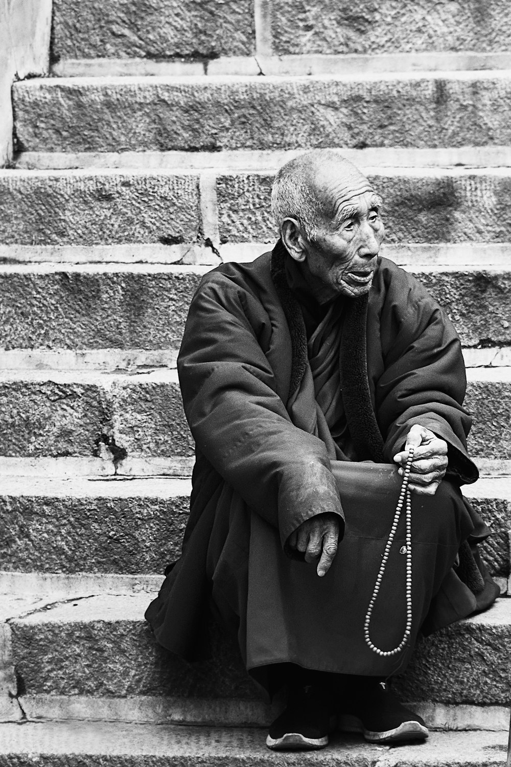 man in black coat standing beside brick wall