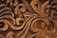 Intricate wooden carvings display detailed scrollwork and leaf motifs with smooth, flowing lines, highlighted by the natural grain and texture of the wood.