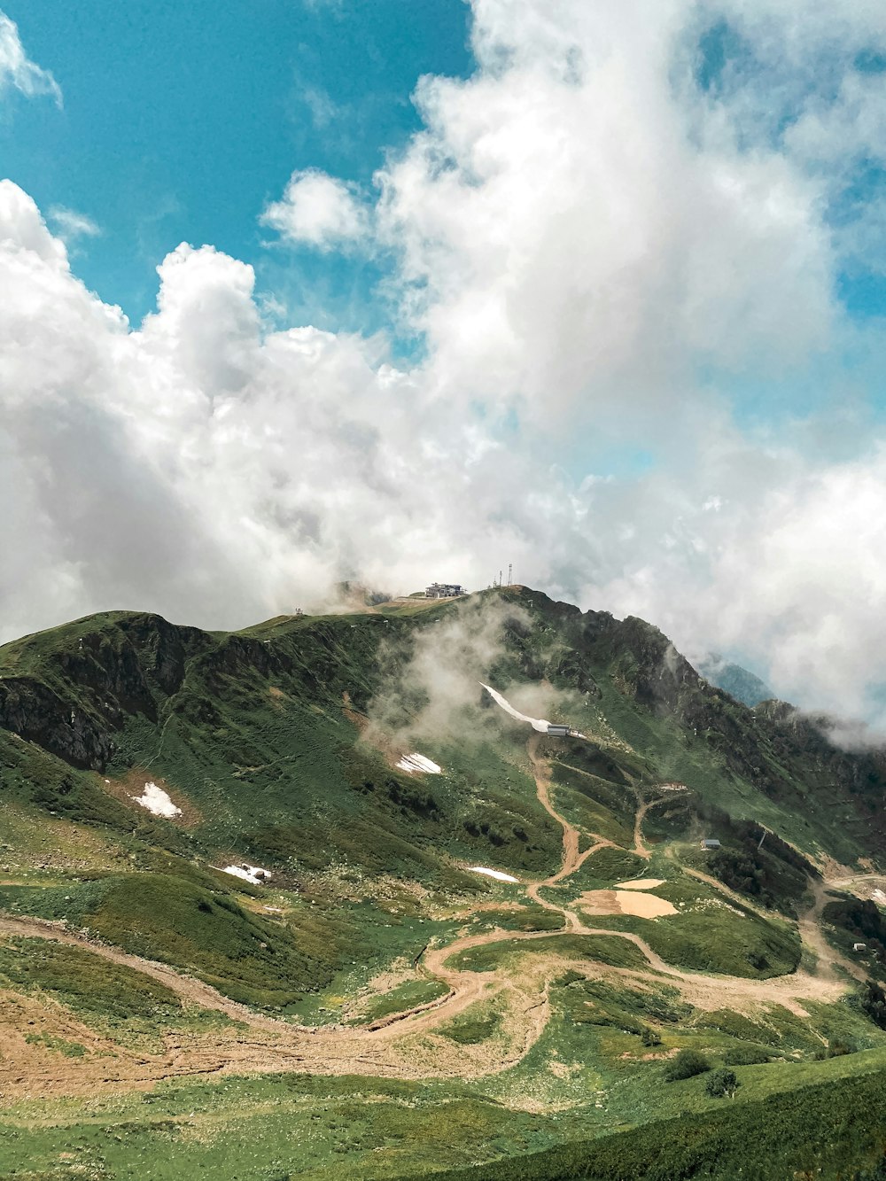 montaña verde y marrón bajo nubes blancas y cielo azul durante el día