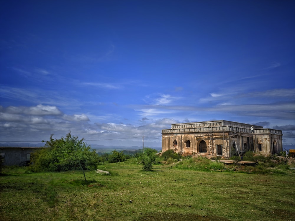 brown concrete building near green grass field under blue sky during daytime