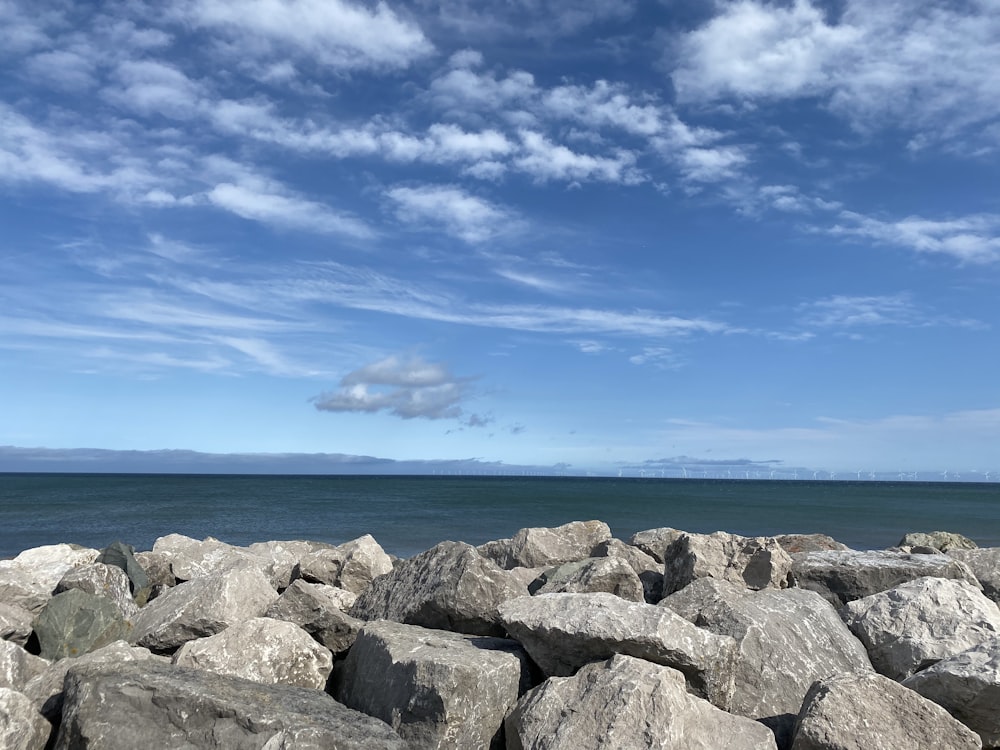 Graue Felsen in der Nähe von Gewässern unter blauem Himmel tagsüber