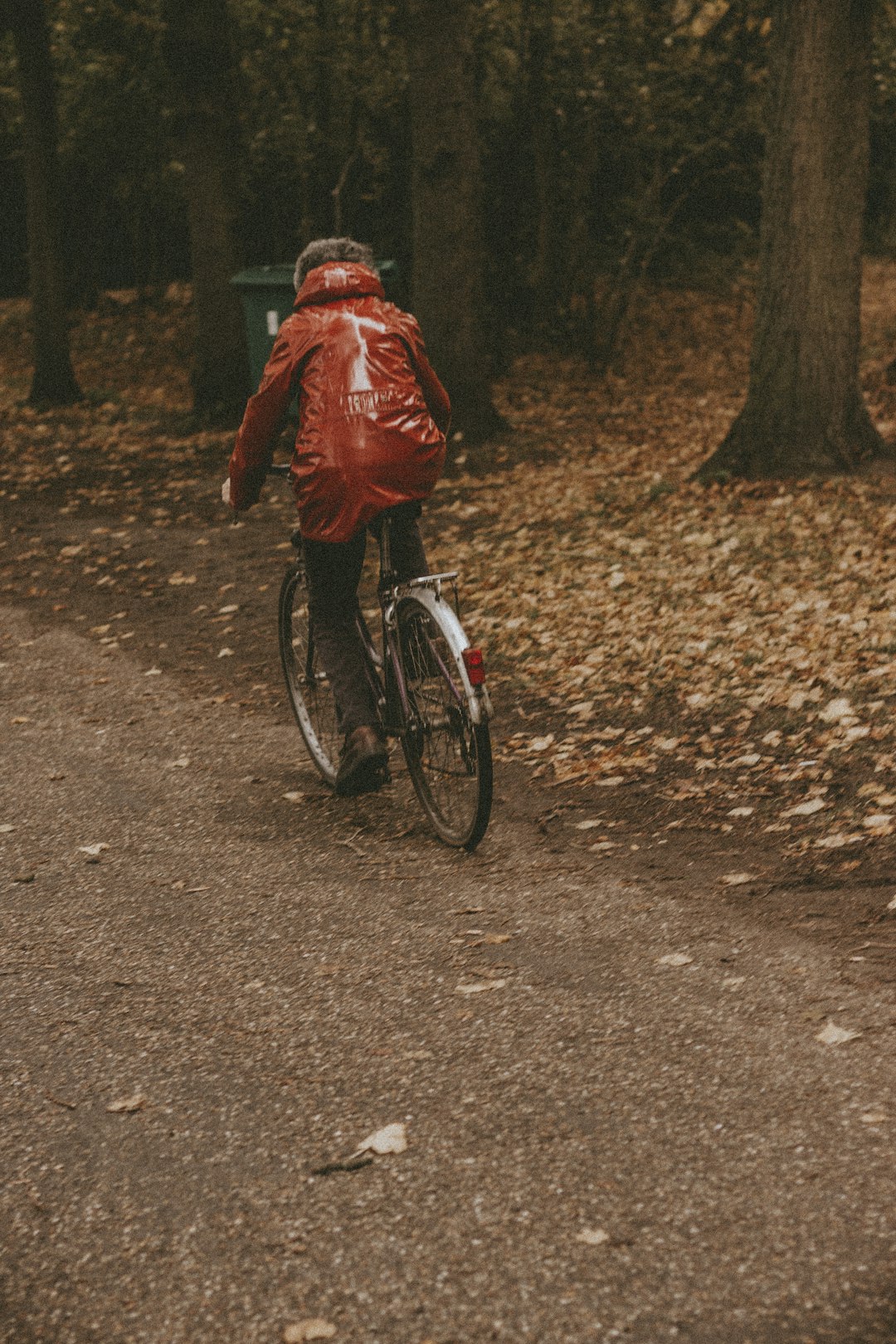 man in red jacket riding bicycle on dirt road during daytime