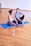 man in white tank top and gray pants sitting on blue yoga mat