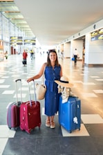 woman in blue denim jacket holding red luggage bag