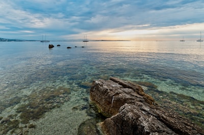 brown rock formation on body of water during daytime