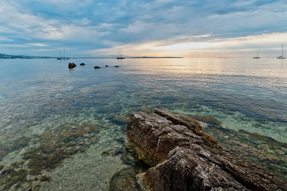 brown rock formation on body of water during daytime