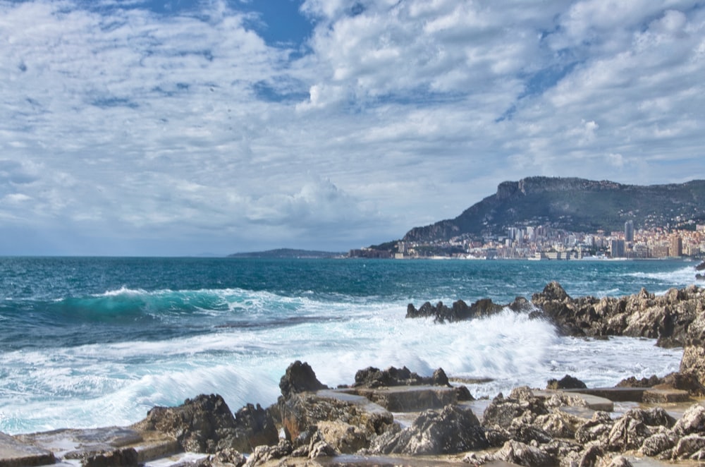 sea waves crashing on rocks under blue and white cloudy sky during daytime