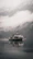 A vintage towboat cutting through misty river waters at dawn, framed by rust-colored autumn leaves.