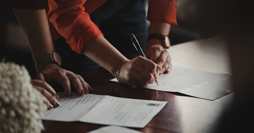 person in orange long sleeve shirt writing on white paper