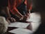 person in orange long sleeve shirt writing on white paper