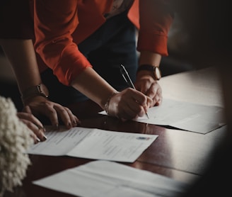 person in orange long sleeve shirt writing on white paper