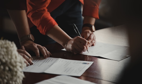 person in orange long sleeve shirt writing on white paper