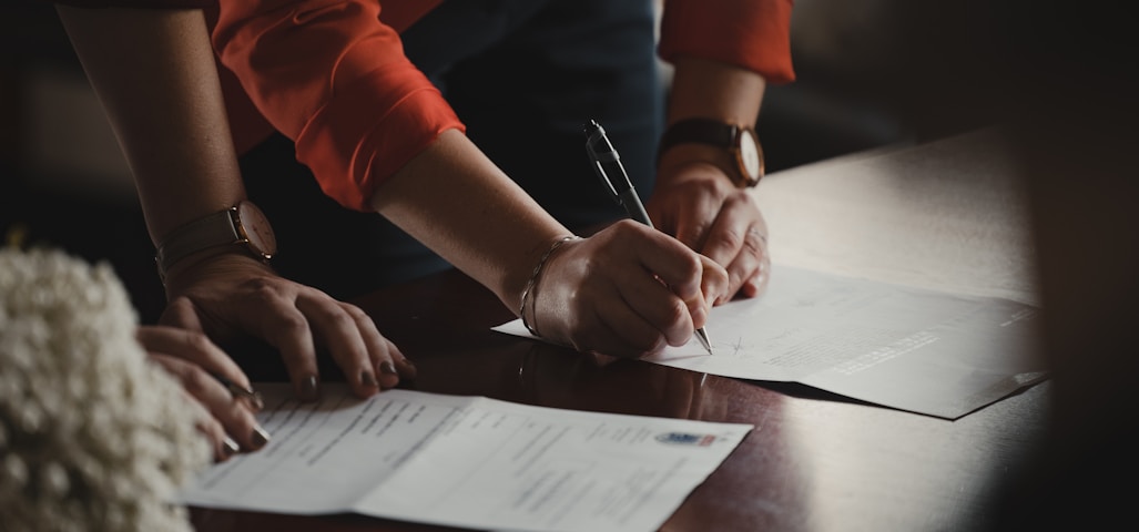 person in orange long sleeve shirt writing on white paper