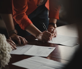 person in orange long sleeve shirt writing on white paper