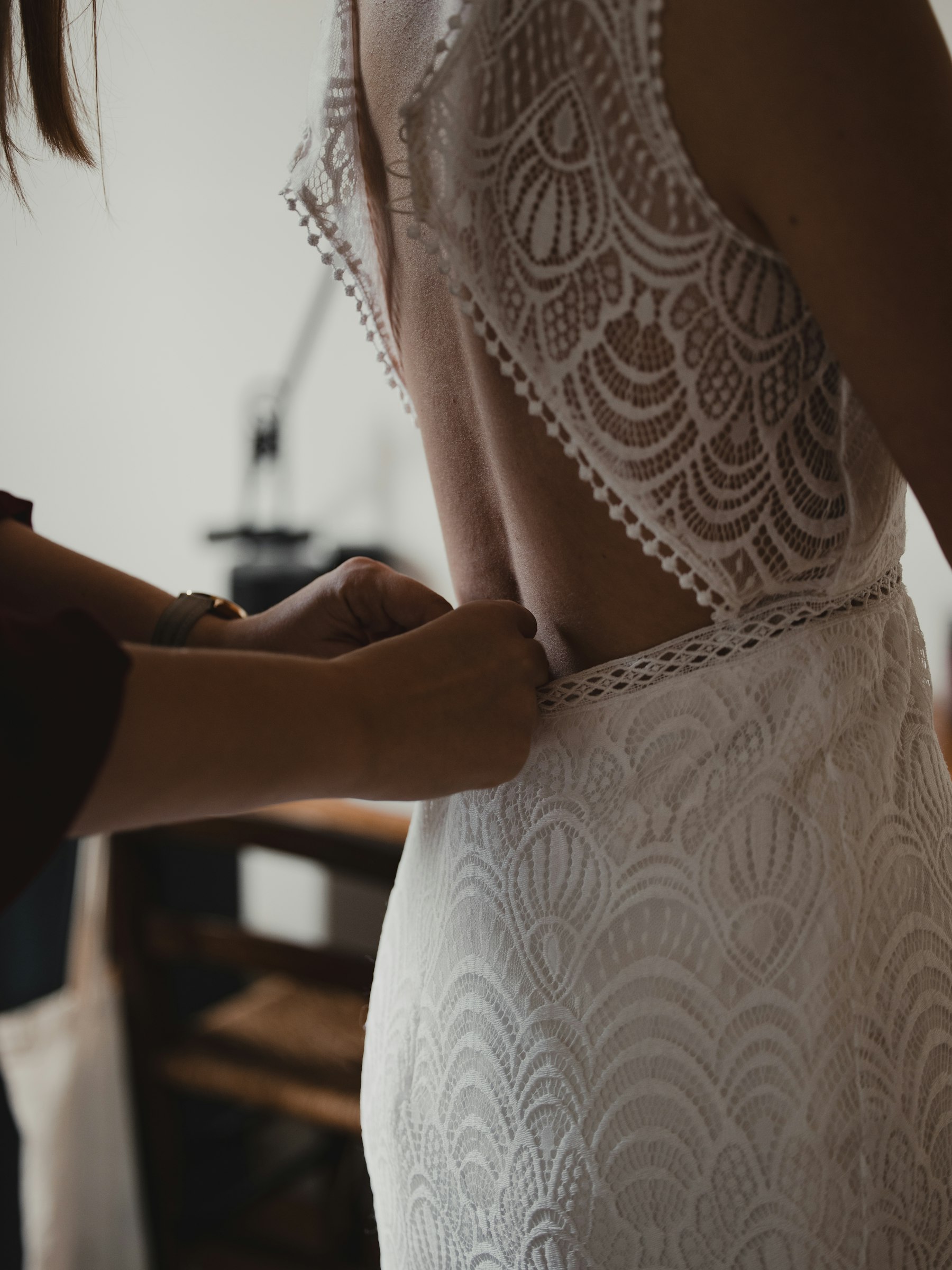 A wedding dress being adjusted by two people before a fitting.