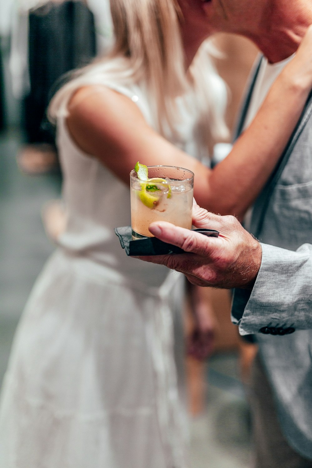 woman in white dress holding drinking glass with yellow liquid